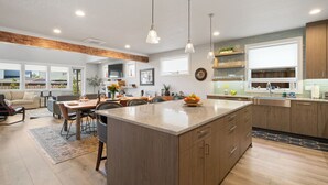Una cocina amplia con una isla grande, armarios de madera e iluminación colgante.