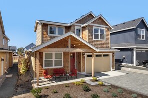 A two-story house with a covered patio, a garage, and a well-maintained front yard.
