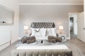 A bedroom with a tufted headboard, two bedside tables with lamps, a bed with a blanket and pillows, and a remote control on the bed. - Birkby Lodge Escape (Lytham St. Anne's)