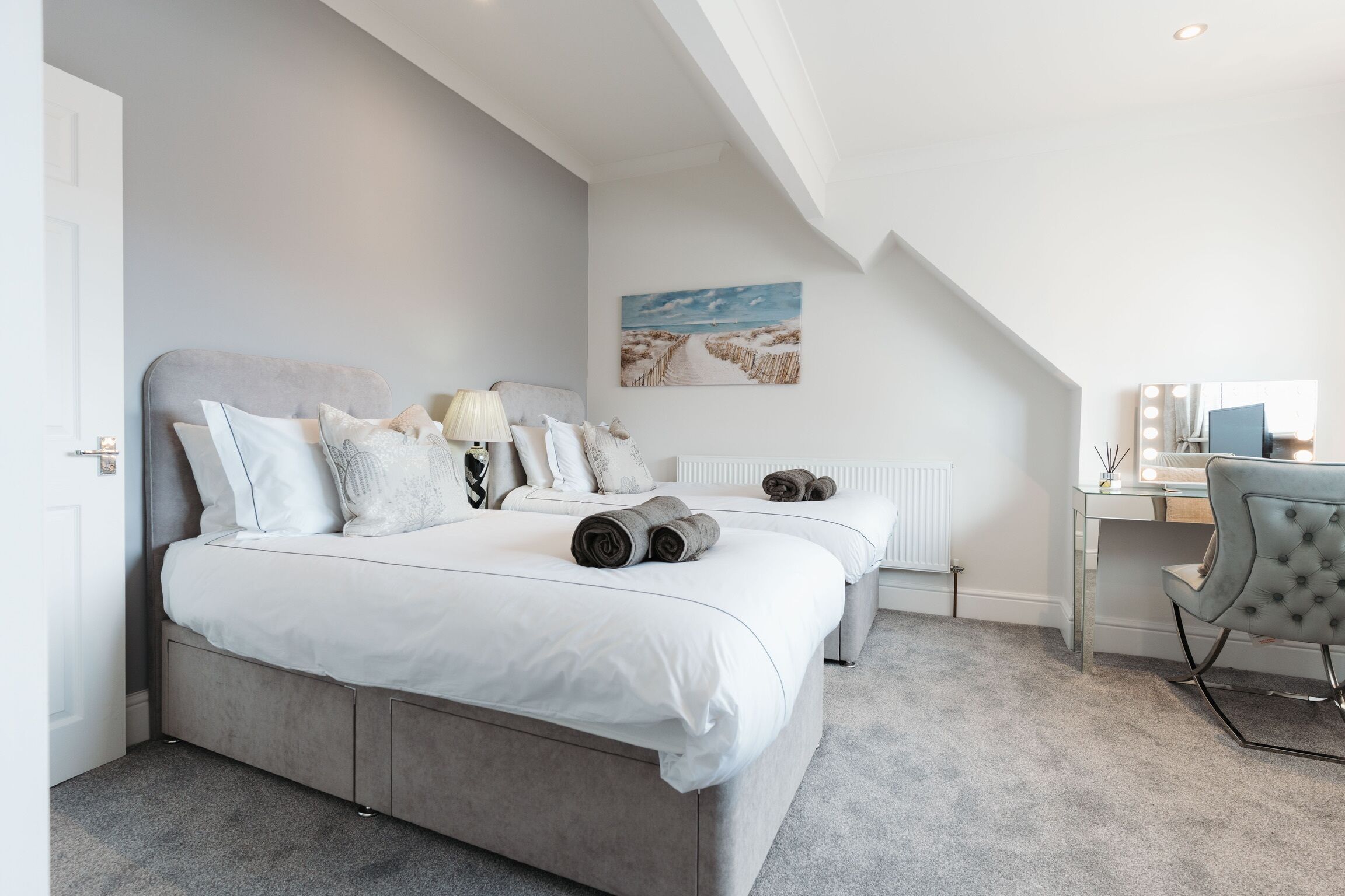 Une chambre avec un grand lit, un bureau avec une chaise et un tableau accroché au mur.