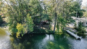 A riverside property with a dock, surrounded by dense trees and a small bridge.
