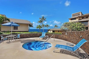 Ein Poolbereich mit Liegestühlen, einem Tisch und Blick aufs Meer.