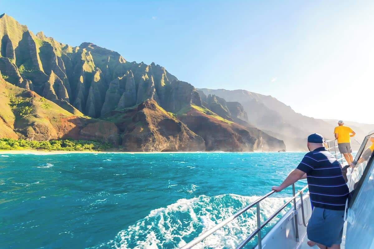 Un bateau sur des eaux turquoise, avec une côte montagneuse en arrière-plan.