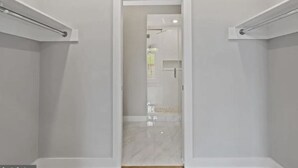 A narrow hallway with a door leading to a bathroom with a glass shower enclosure. - Lavish Penthouse with Private Rooftop+Views of Capitol&Monument+Parking (Washington)