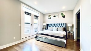 A bedroom with a large bed, a nightstand, a lamp, and a door leading to a balcony. - Lavish Penthouse with Private Rooftop+Views of Capitol&Monument+Parking (Washington)