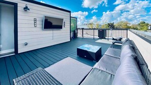 A modern outdoor deck with a flat-screen TV, a sofa, and a dining table. - Lavish Penthouse with Private Rooftop+Views of Capitol&Monument+Parking (Washington)