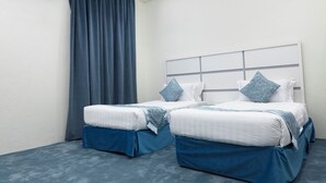 A hotel room with two beds, a large window with curtains, an air conditioning unit, and a ceiling light. - Garden View Hotel (Tabuk)