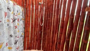 Une cabine de douche en bambou avec un sol carrelé et un pommeau de douche.