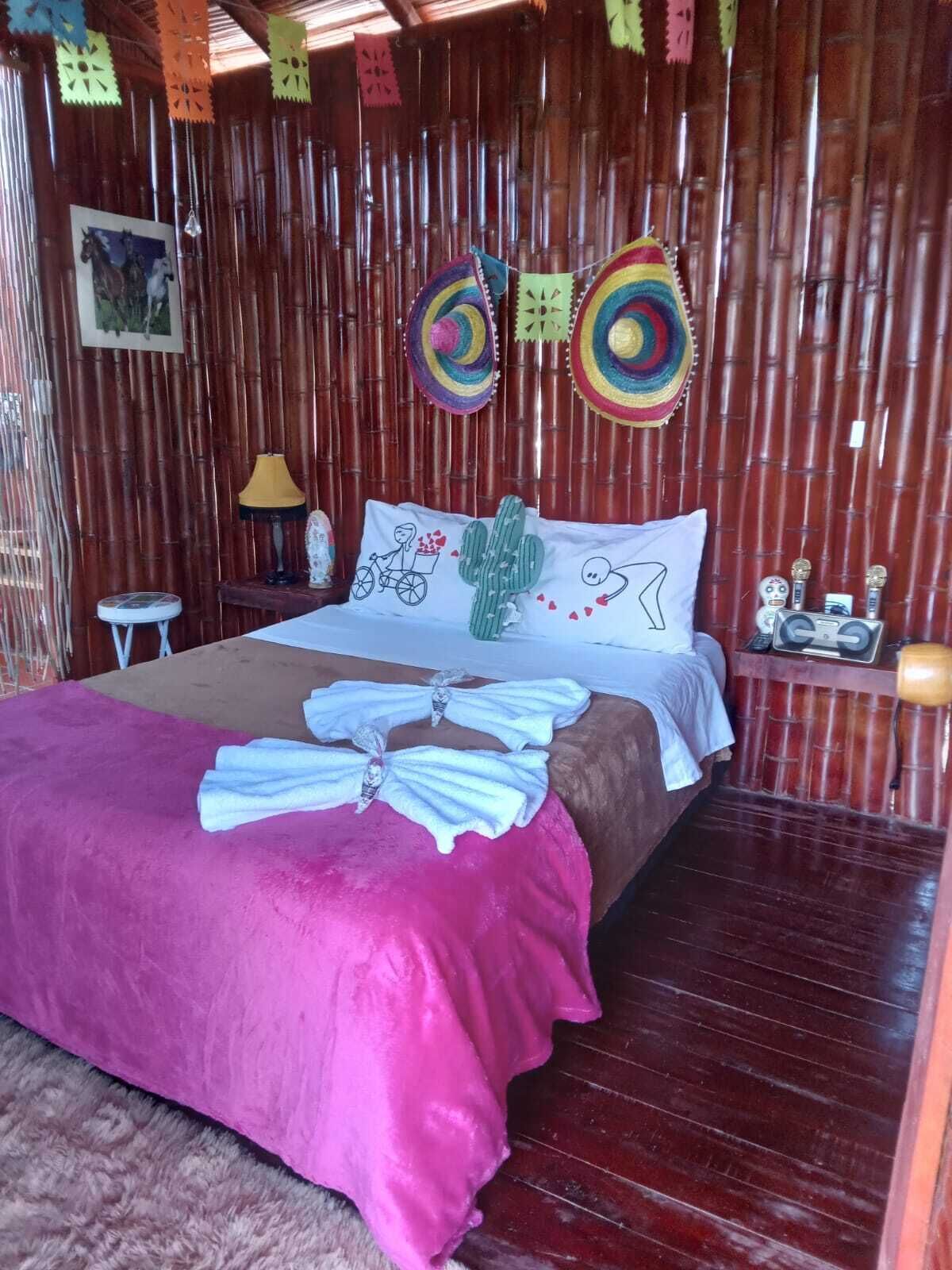 A room with a bed, a nightstand, a lamp, and a wall decorated with colorful paper cutouts.
