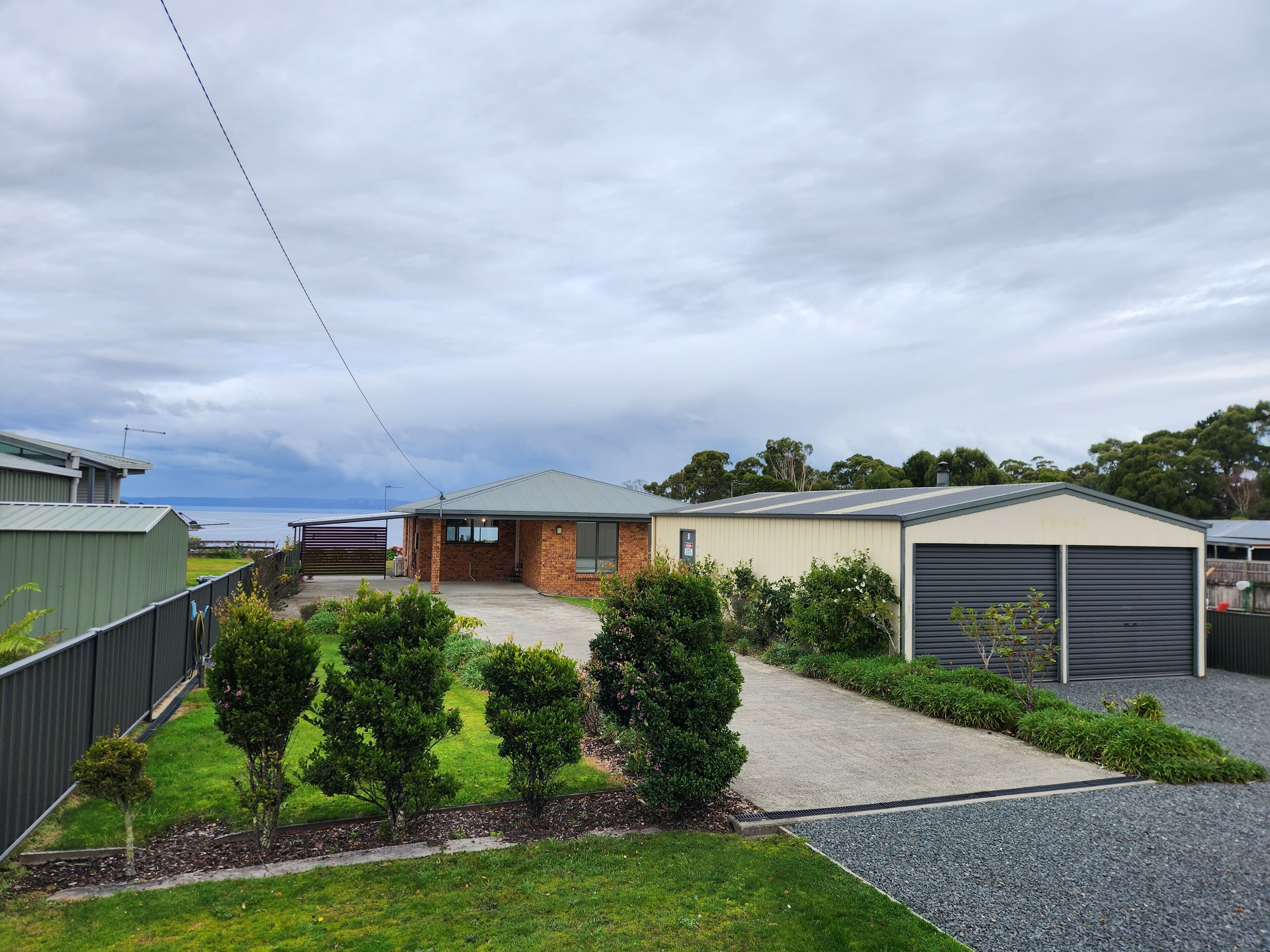 A residential area with a house, garage, and a view of the sea.
