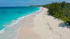 Une plage aux eaux turquoise et limpides, bordée d’un rivage sablonneux.