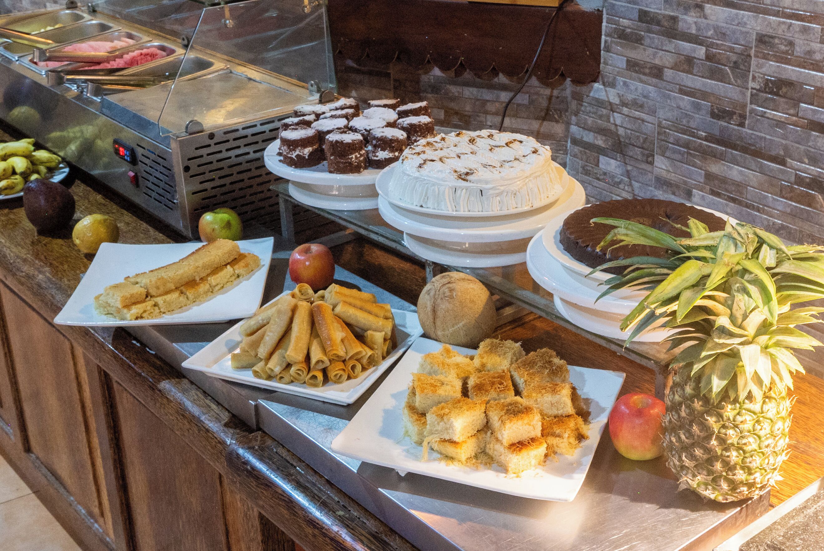 A buffet with various food items including cakes, pastries, and fruits.