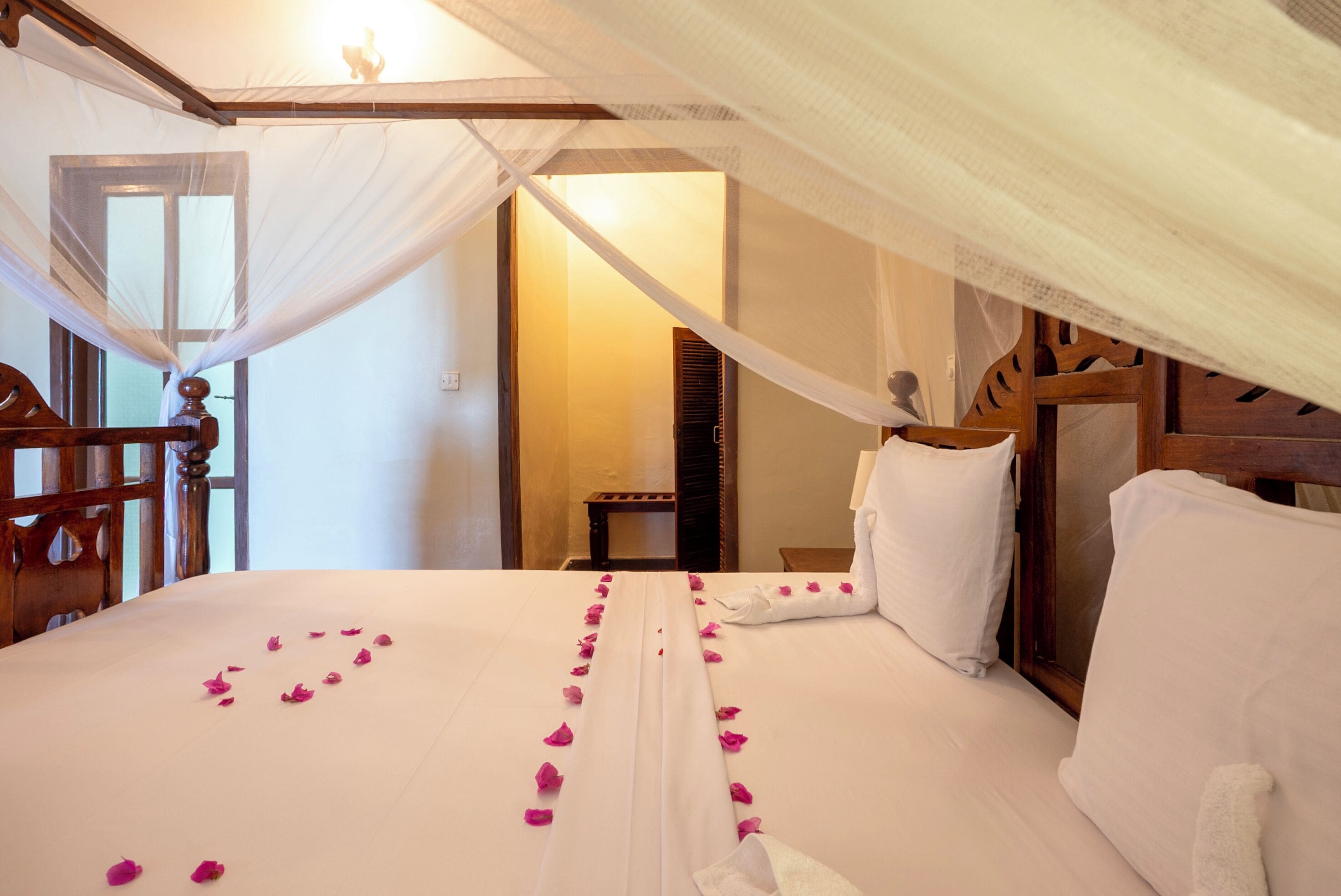 A hotel room with a bed, a wooden headboard, a nightstand, and a window with a view.