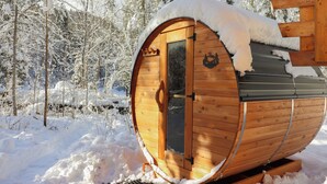 A wooden sauna in a snowy forest.