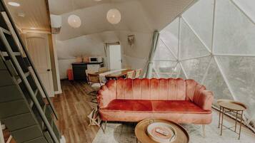 Ein gemütliches Wohnzimmer mit einem roten Sofa, einem Couchtisch und einem Essbereich mit Tisch und Stühlen.