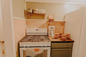 A compact kitchen with a gas stove, a coffee maker, and a microwave.