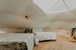 A cozy attic bedroom with a sloped ceiling, two beds with floral bedding, a hanging light fixture, and a wooden ladder. - Slate Crossing: Creekside Dome (Cosby)