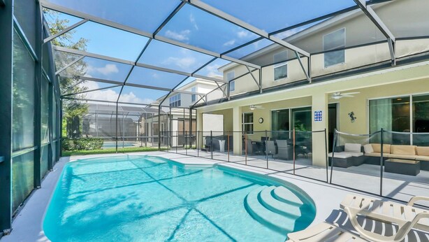 A covered outdoor swimming pool with lounge chairs and a glass-enclosed building.