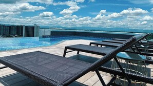 Un área de piscina en la azotea con sillones y vistas al horizonte de la ciudad.
