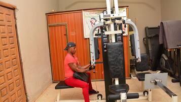 A man exercising on a bench in a gym with a weight machine, a wooden door, and a poster on the wall.
