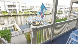 A balcony with a view of a marina, a flag, and a chair.