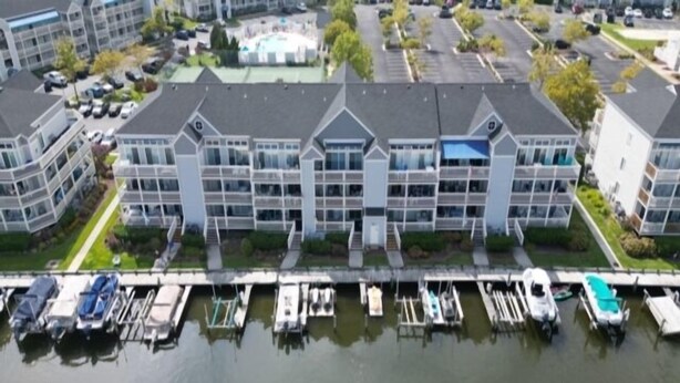 A multi-story hotel with a marina docked in front, featuring a swimming pool and parking area.