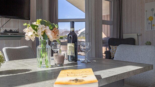 A dining table with a wine bottle, glasses, and a book.