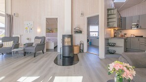 A modern interior with a fireplace, seating area, kitchen, and a skylight.