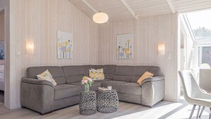 A modern living room with a grey sectional sofa, two round side tables, and a large window providing natural light.