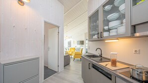 A modern kitchen with a dishwasher, a sink, and a glass cabinet with dishes.