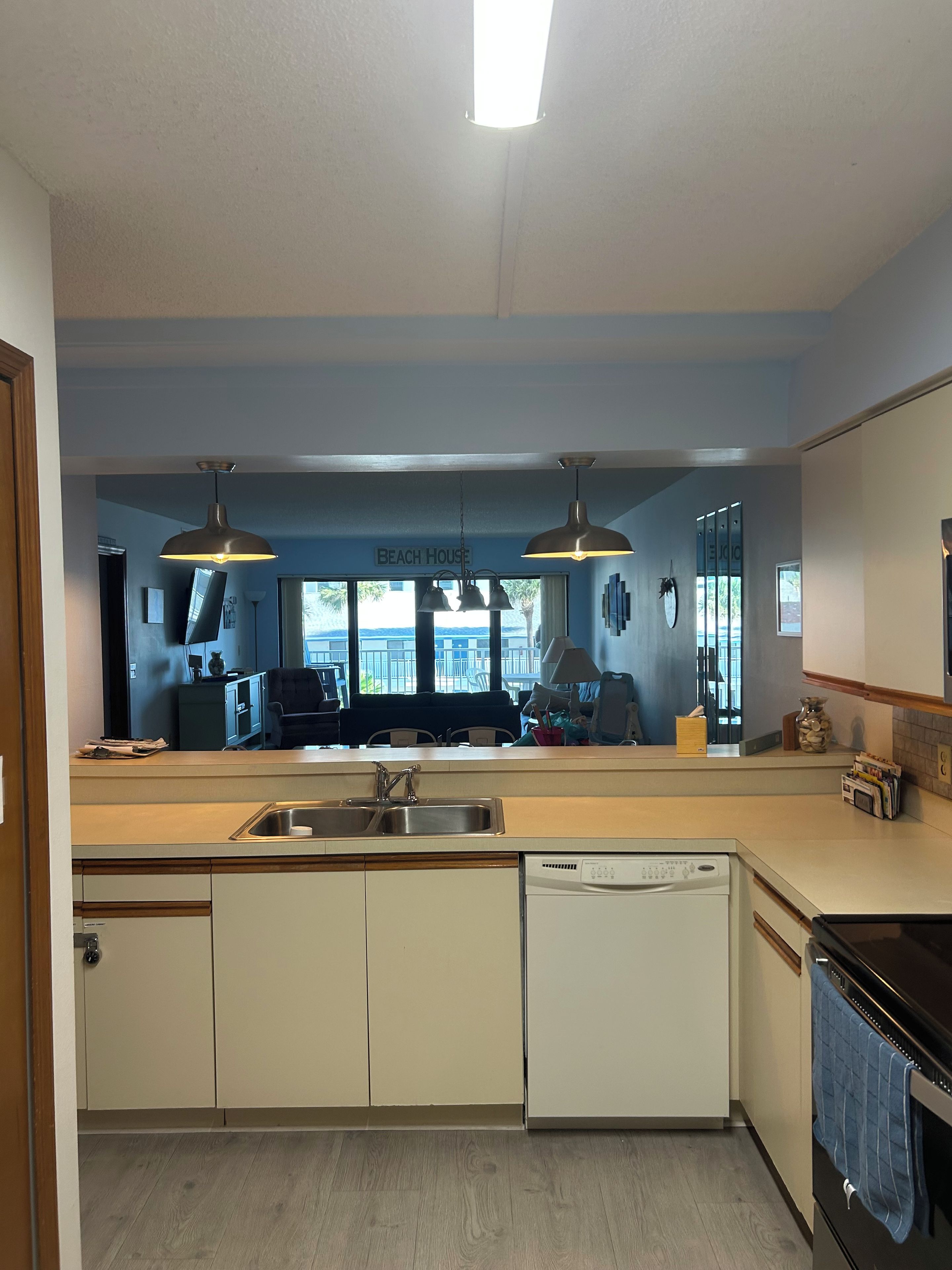 A modern kitchen with a central island, double sink, and overhead pendant lighting.