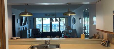 A modern kitchen with a central island, double sink, and overhead pendant lighting.