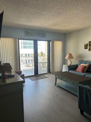 A living room with a sofa, a coffee table, a lamp, and a sign reading 'Beach House'.