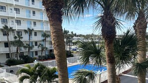 Un hôtel à plusieurs étages, doté d’une piscine et bordé de palmiers.