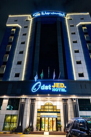 A hotel with a prominent entrance, a neon sign, and flags. - ODST Jed (Jeddah)