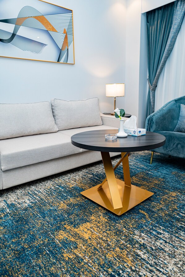 Een moderne hotelkamer met een ronde tafel, een bank, een lamp en een schilderij aan de muur.