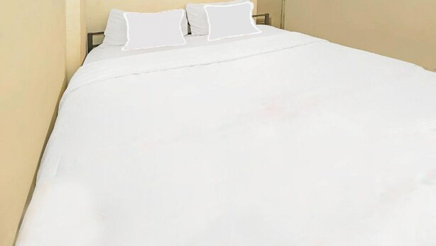 A bed with white bedding and two pillows. - Backpacker Homestay Cibubur by PEKOTEL (Bekasi)