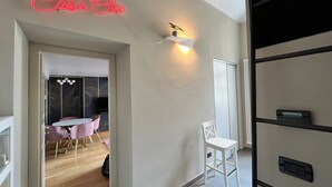 A modern interior with a neon sign reading "Casa Chic," a dining area with pink chairs, and a white wall-mounted light fixture. - Chic Turin house in the historic center (Torino)