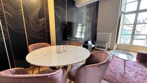 A modern room with a round table, cushioned chairs, a flat-screen TV, and a radiator. - Chic Turin house in the historic center (Torino)