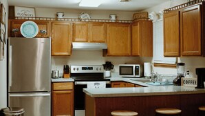 A kitchen with wooden cabinets, a stainless steel refrigerator, an oven, a microwave, and a coffee station. - Charlotte's Cove - Right in the Heart of Amish Country (Millersburg)