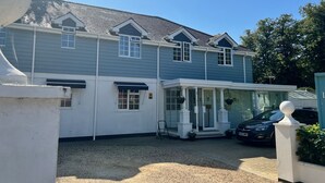 Une maison à deux étages avec un porche couvert et une voiture garée dans l’allée.