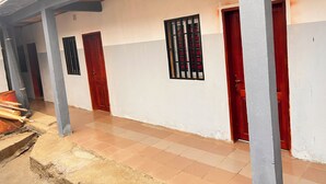Um edifício com piso de azulejos, galeria coberta e várias portas e janelas.