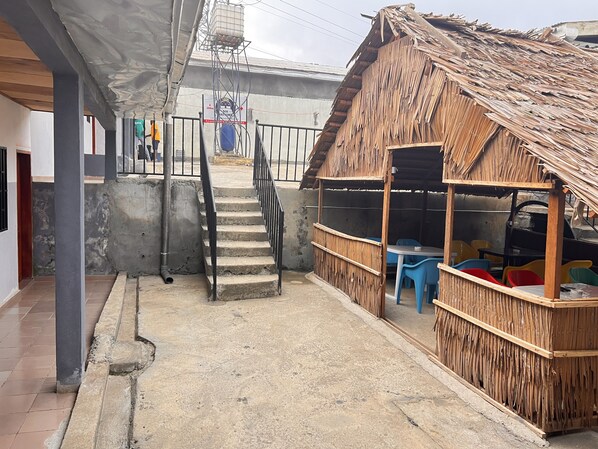 A narrow alleyway with a concrete staircase leading to a building with a thatched roof.