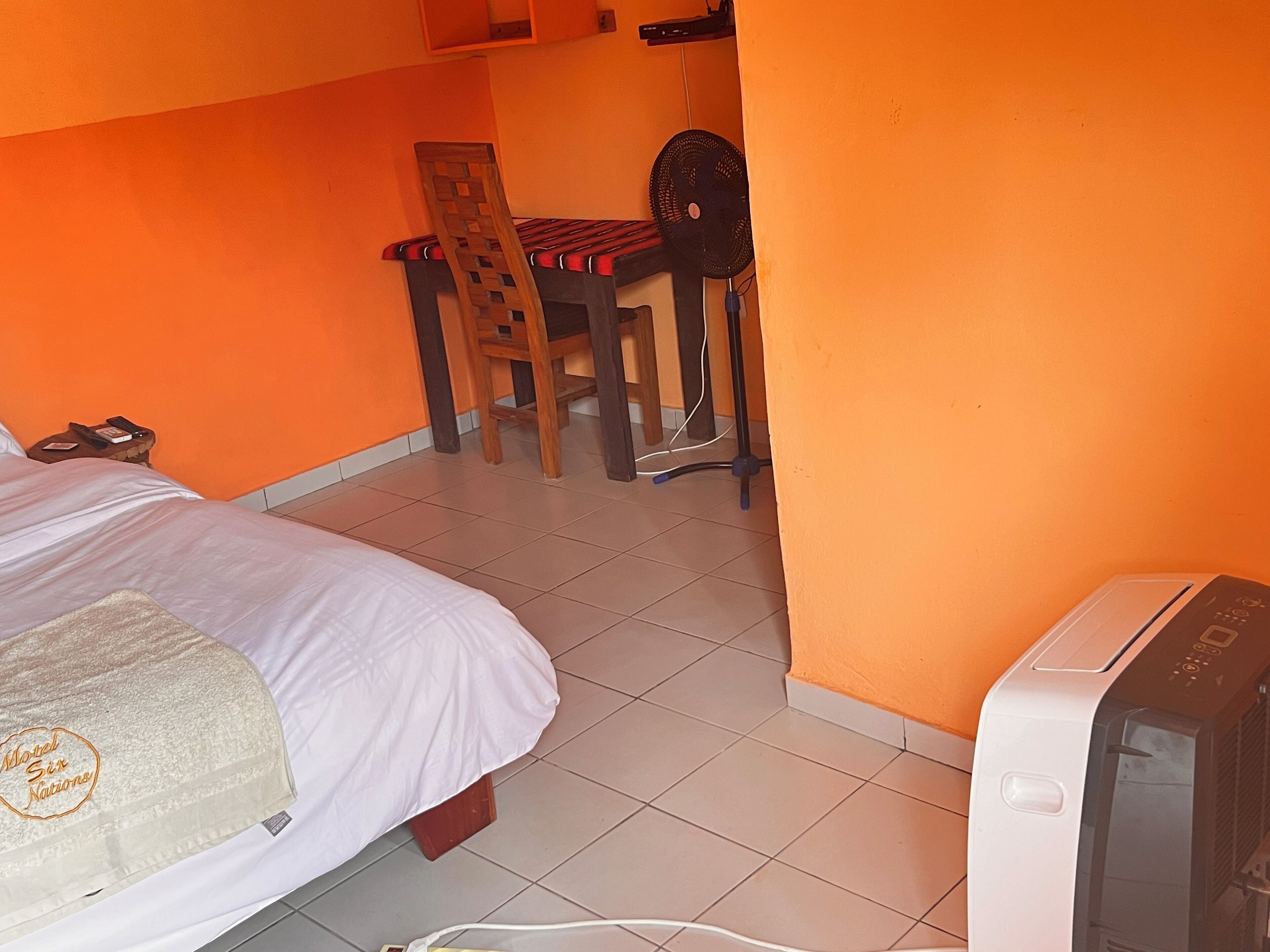 A hotel room with a bed, a desk with a chair, and a television.