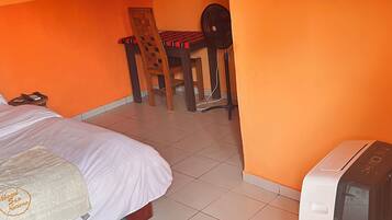 A hotel room with a bed, a desk with a chair, and a television.