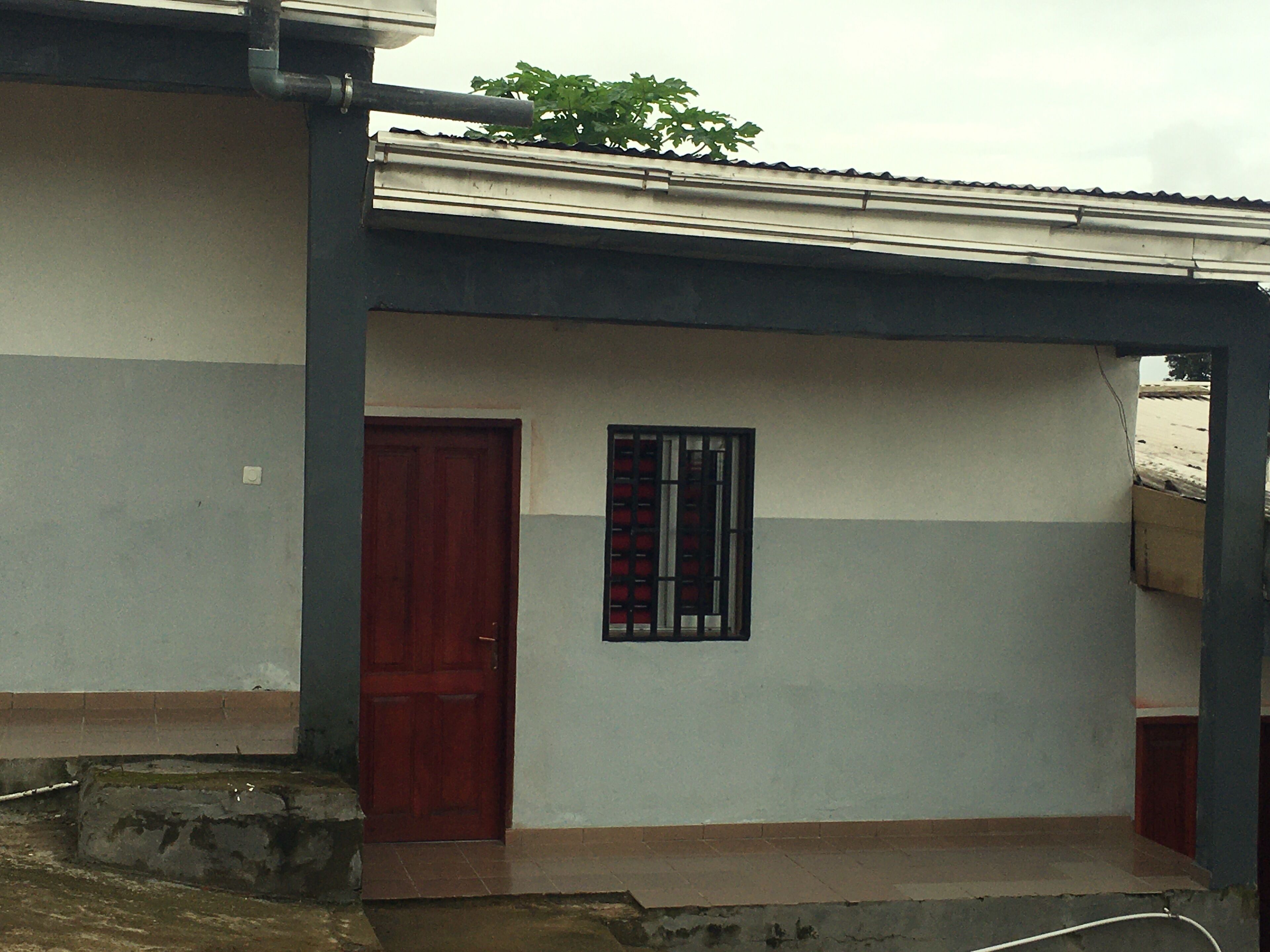 A building with a red door and a window with vertical bars.