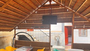 Um espaço interno com teto alto, uma mesa com cadeiras e uma escada que leva a um andar superior.