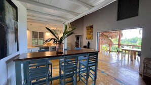 Una cocina amplia con una isla central, taburetes de bar y vistas al exterior.