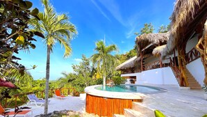 Un resort con piscina, sillones de descanso y una estructura de techo de paja.
