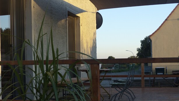 Un espace patio agrémenté d’une clôture en bois, de chaises en métal et d’une plante en pot.